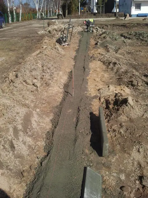 Wąski wykop z wykonaną betonową ławą fundamentową wzdłuż linii przyszłej konstrukcji