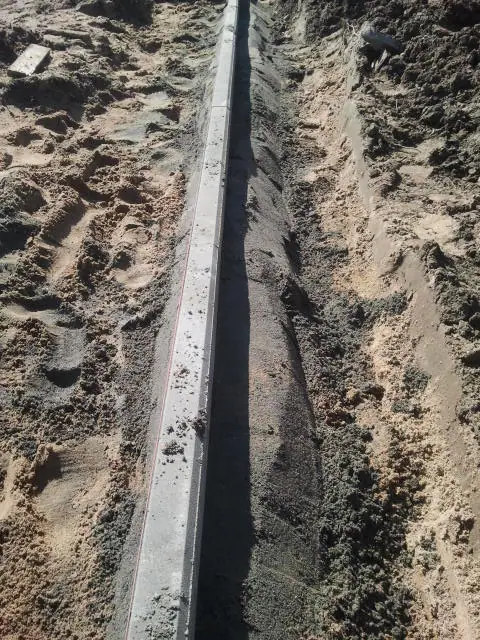 Prosty wykop z ułożonym krawężnikiem betonowym na obrzeżu przyszłego boiska