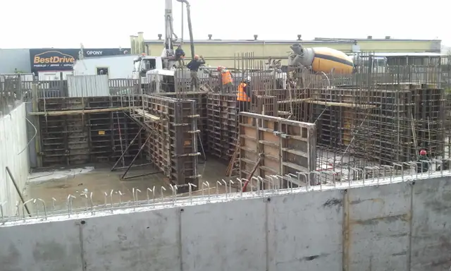 Betonowanie ścian fundamentowych pompą do betonu przy szalunkach na Osiedlu Bursztynowym
