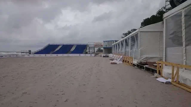 Puste niebieskie trybuny widowni osłonięte namiotami na plaży przed zawodami Cavaliada w Kołobrzegu
