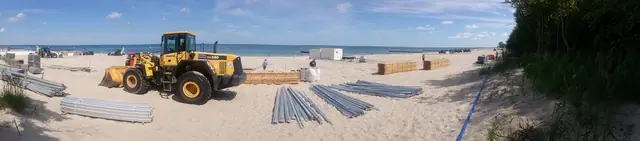 Ładowarka Komatsu przy rozładunku elementów konstrukcji trybun na plaży przed zawodami Cavaliada w Kołobrzegu