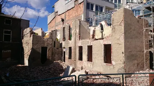 Częściowo rozebrany budynek bez dachu, odsłonięte wnętrza dawnych mieszkań