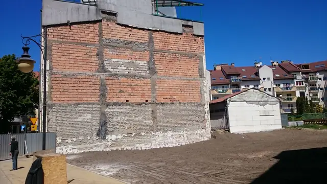 Pozostała ceglana ściana sąsiedniego budynku na uporządkowanym placu po rozbiórce