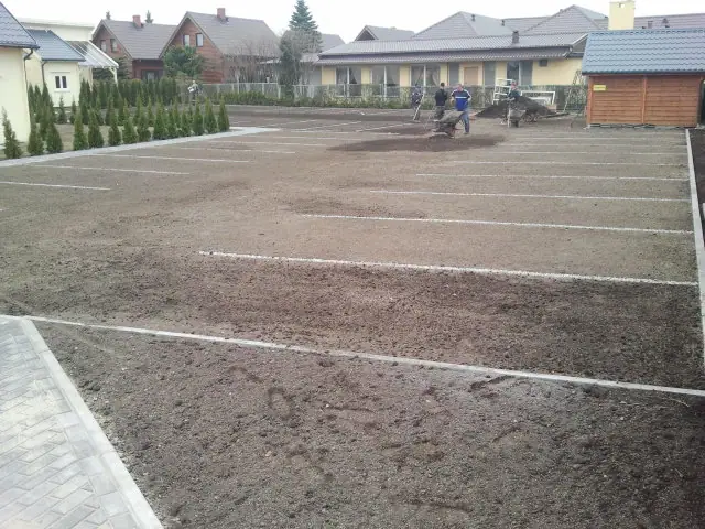 Rozległy żwirowy parking z wymalowanymi liniami czeka na ułożenie kostki przy domkach