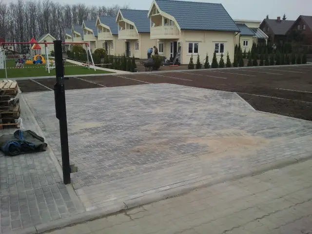 Ukończony ciemny parking z kostki widziany od strony placu zabaw i domków letniskowych