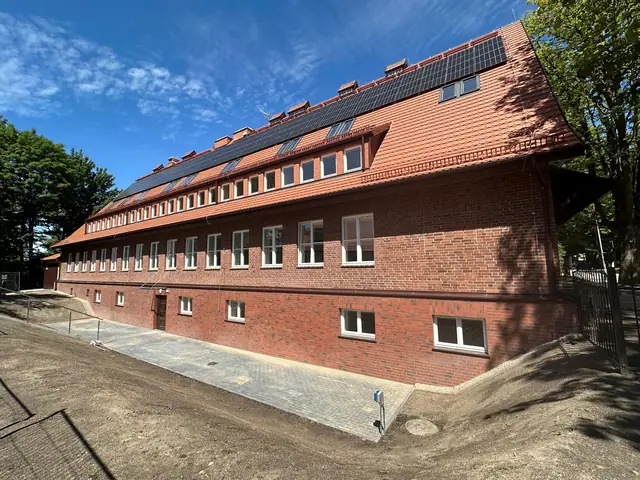 Widok całej elewacji z panelami fotowoltaicznymi na dachu i jeszcze niewykończonym terenem wokół