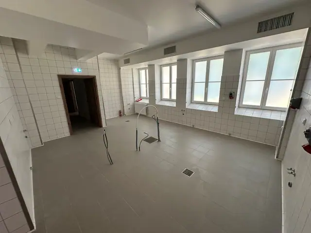 Niewykończone pomieszczenie z białymi kafelkami i odsłoniętą instalacją wodną w ścianie