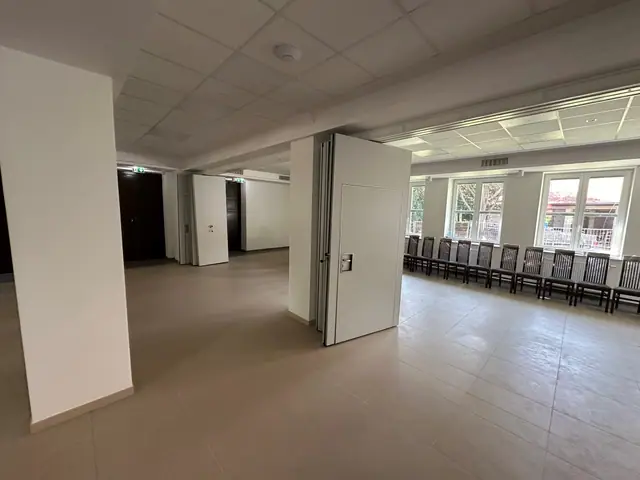 Przestronna sala z białymi filarami i rzędem krzeseł ustawionych po remoncie