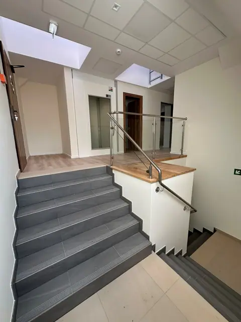 Schody na antresolę ze szklaną poręczą i podłogą w odcieniu drewna po remoncie