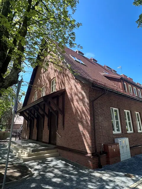 Zadaszone drewniane wejście do budynku z kamiennymi schodami po termomodernizacji