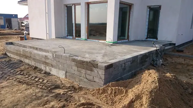 Murowany cokół tarasu przy przeszklonym narożniku domu jednorodzinnego