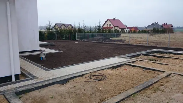 Obsypana czarną ziemią działka wokół domu z obrzeżami pod przyszły trawnik