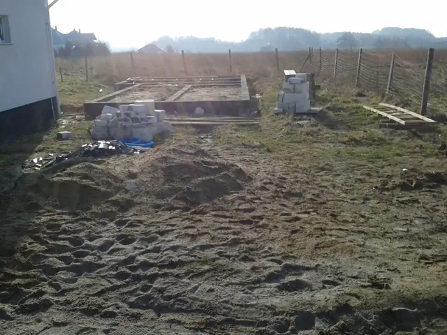 Zarys wykopu fundamentowego pod ogrodzenie działki z ułożonymi już pustakami betonowymi