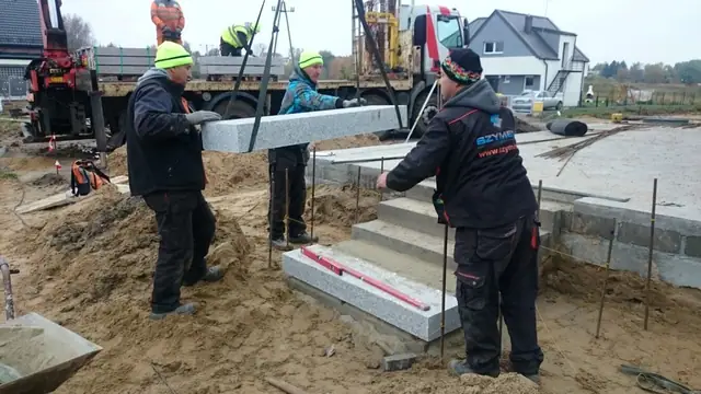 Dźwig ustawia prefabrykowany element granitowych schodów zewnętrznych przy domu