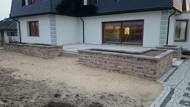 Ukończone podwórko z dwiema murowanymi donicami i kostką ułożoną w esowaty wzór