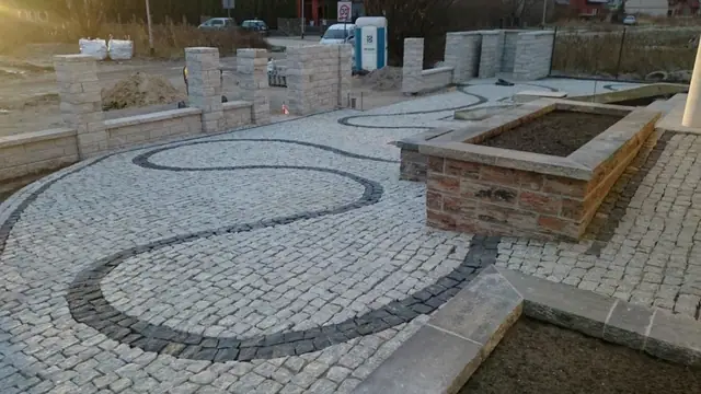 Granitowe schody i esowaty wzór kostki brukowej przy narożniku domu jednorodzinnego