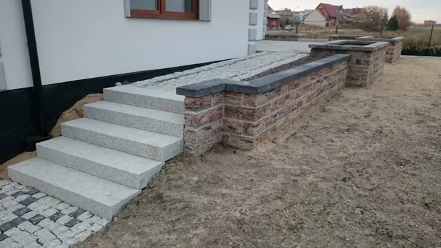Kamienne słupki ogrodzeniowe przy niemal gotowym podjeździe z kostki
