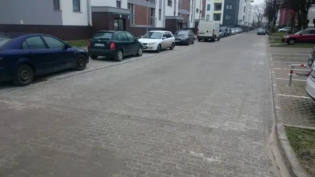 Gotowa ulica wewnętrzna z kostki brukowej z zaparkowanymi samochodami na ulicy Wielkopolskiej w Kołobrzegu