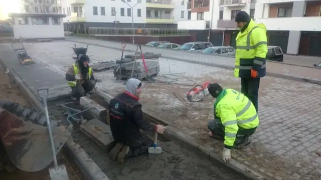 Robotnicy układają krawężnik przy nowej nawierzchni z kostki na ulicy Wielkopolskiej w Kołobrzegu