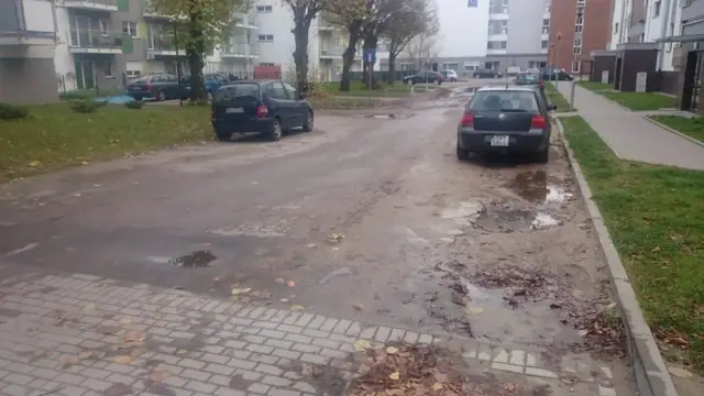 Zniszczona nawierzchnia asfaltowa z kałużami obok zaparkowanych samochodów na ulicy Wielkopolskiej w Kołobrzegu