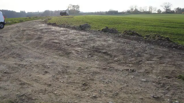 Wyrównany fragment drogi gruntowej na polu ze śladami pracy koparki