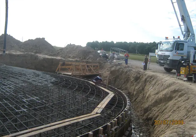 Zbrojenie kolistego fundamentu turbiny wiatrowej, w tle pompa do betonu na budowie