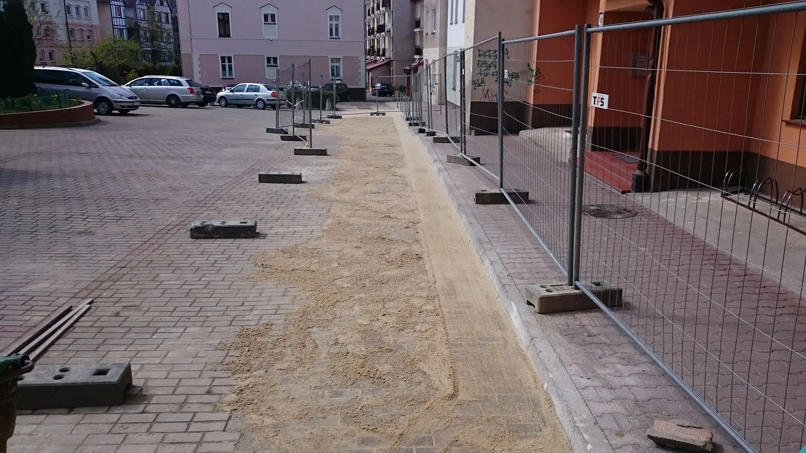 Robotnicy firmy brukarskiej układają kostkę brukową na parkingu w Kołobrzegu