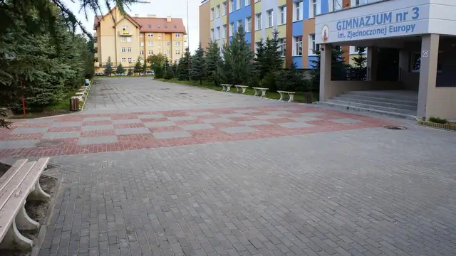 Plac w szachownicę przed wejściem do Gimnazjum nr 3 z widocznym szyldem szkoły