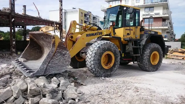 Ładowarka kołowa Komatsu ładuje gruz łyżką na placu po rozbiórce hurtowni
