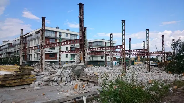 Stalowy szkielet konstrukcji hali na tle nowego osiedla mieszkaniowego