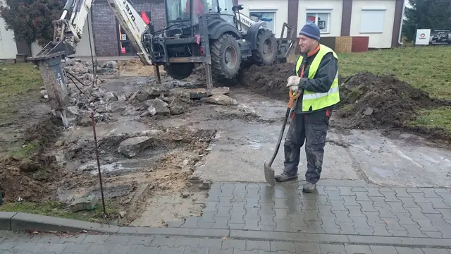 Pracownik przygotowuje podłoże pod nowy chodnik po rozebraniu starej nawierzchni przy Inter Cars