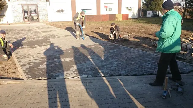 Brukarze układają kostkę betonową na chodniku przed wejściem do sklepu Inter Cars w Kołobrzegu
