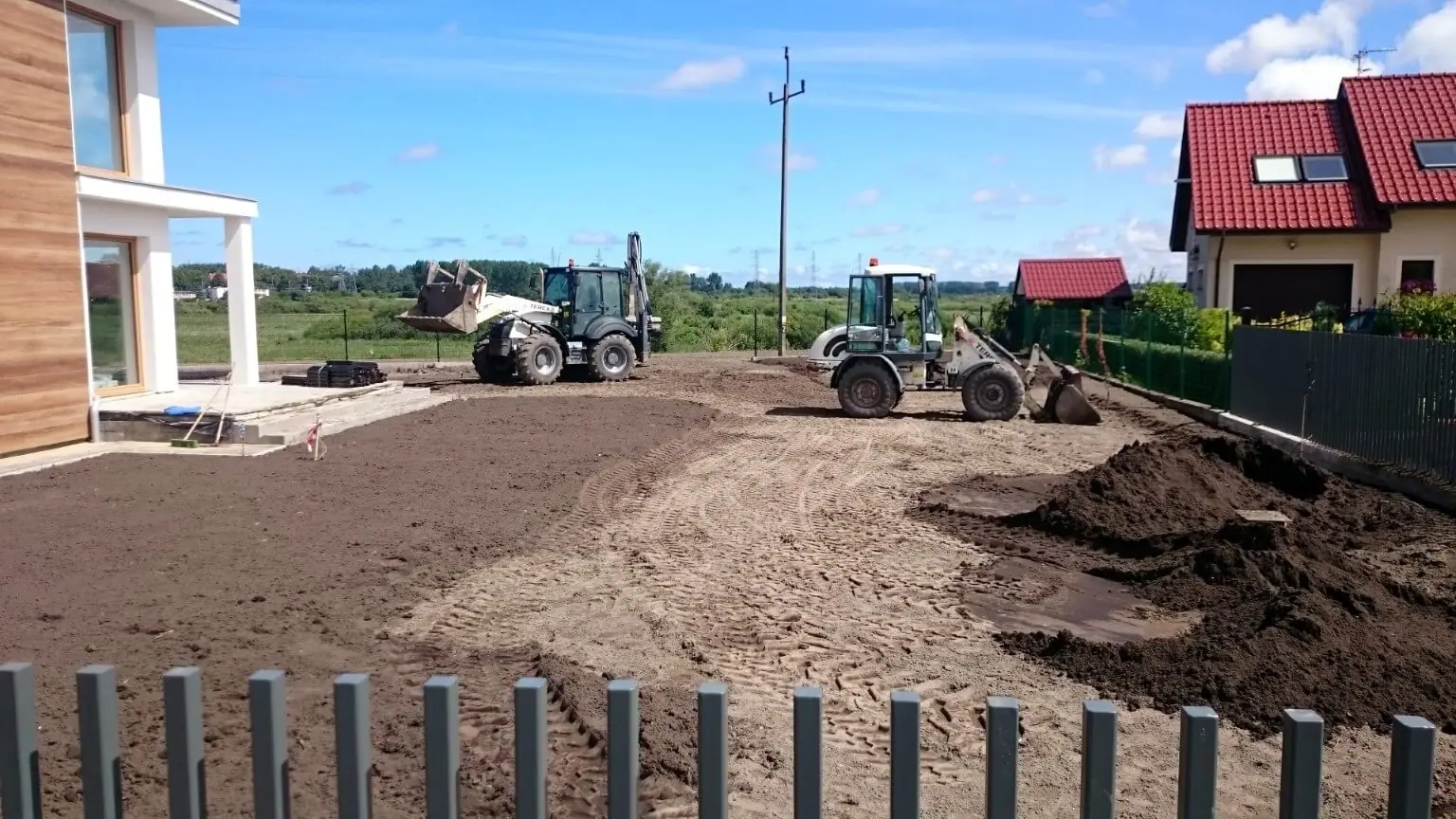 Koparki rozplantowują ziemię urodzajną przed domem po zakończeniu budowy