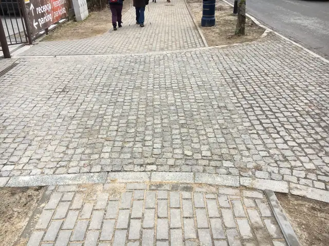 Falisty ciąg pieszy z kostki granitowej prowadzący wzdłuż skarpy przy jezdni