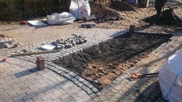 Świeżo wypełniona zaprawą szczelina w nawierzchni z kostki brukowej przy worku z materiałem