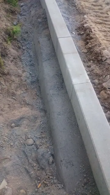 Nowo ułożony krawężnik betonowy z widoczną podsypką na ulicy Sienkiewicza w Kołobrzegu