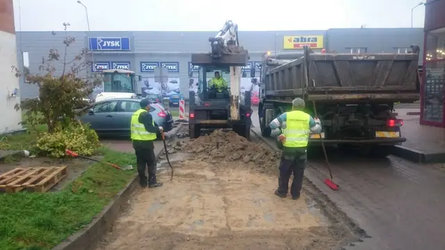 Wywrotka rozładowuje ziemię, robotnik zamiata chodnik podczas prac na ulicy Sienkiewicza w Kołobrzegu
