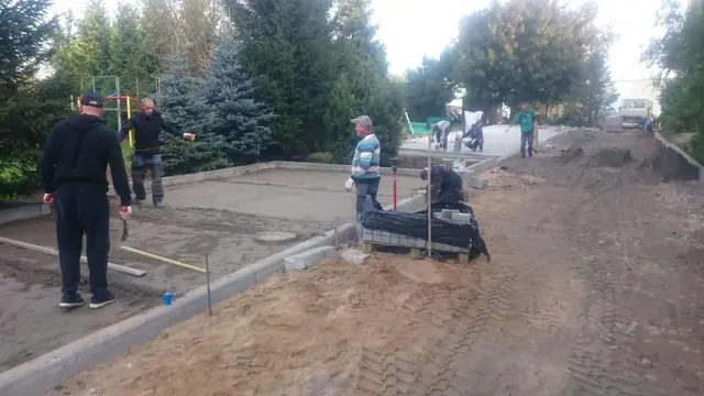 Robotnicy zacierają świeżo wylaną nawierzchnię betonową na placu przy ulicy Sienkiewicza w Kołobrzegu