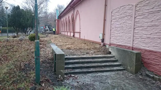 Schody i chodnik przy różowej elewacji kościoła na jeszcze niewykończonym terenie
