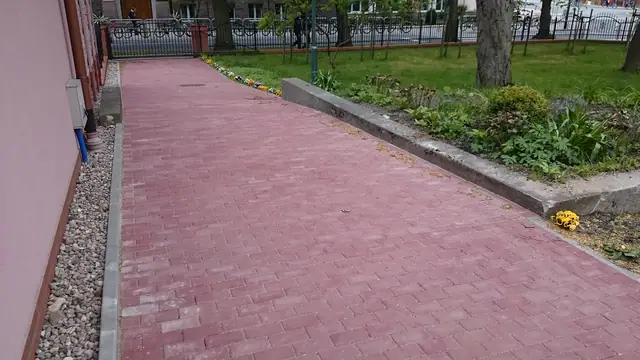 Wybrukowana ścieżka przy wejściu bocznym kościoła z rabatą żwirową wzdłuż muru