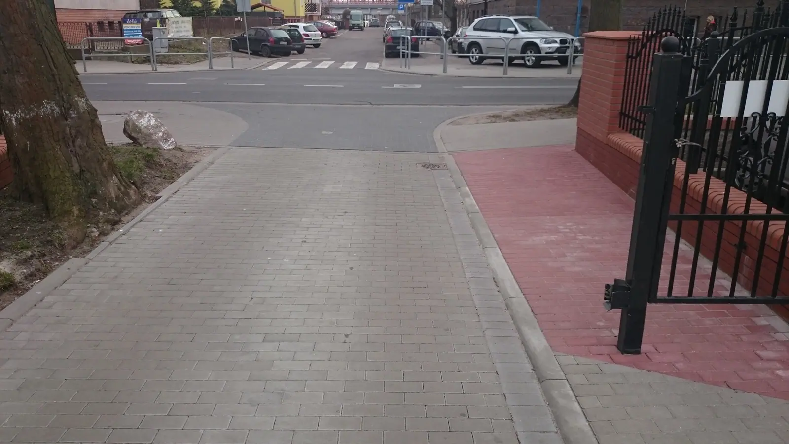 Wjazd z kostki brukowej przy metalowej bramie ogrodzeniowej; montaż bramy przesuwnej także wymaga uzgodnienia poziomu przejazdu z nawierzchnią.