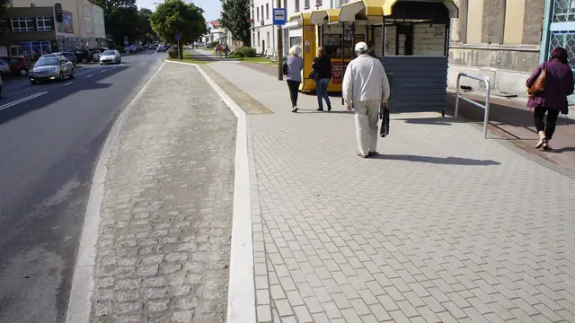 Ułożona jasna kostka chodnika obok starego bruku kamiennego przy krawężniku w Koszalinie