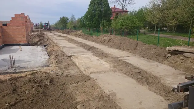 Betonowe segmenty drogi układane na podbudowie żwirowej wśród domów w budowie Rezydencji Magnolia