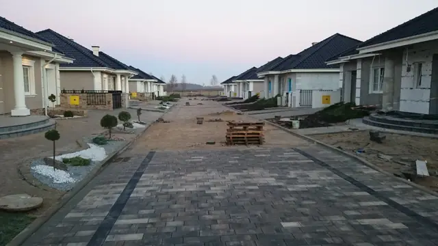 Wybrukowana ulica pomiędzy rzędami domów ozdobiona kamiennymi rabatami przy wejściach