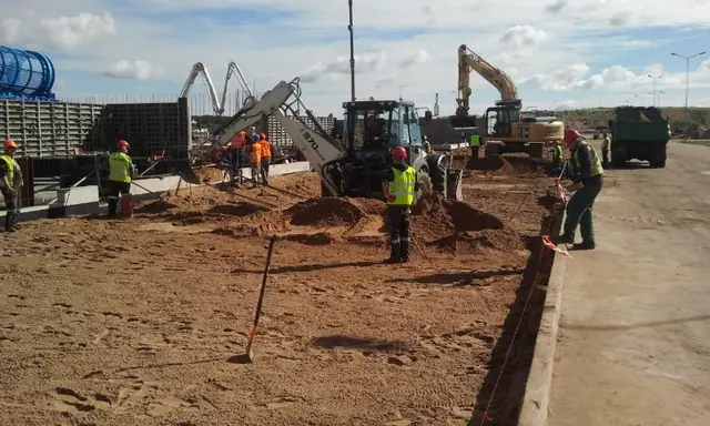 Pompa do betonu i koparka pracują razem, gdy ekipa betonuje wzdłuż wyznaczonej linii