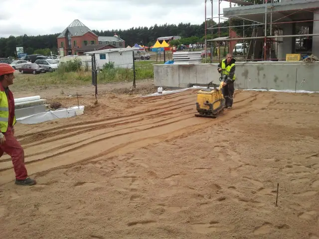 Pracownik zagęszcza piaszczystą ścieżkę zagęszczarką w pobliżu wesołego miasteczka