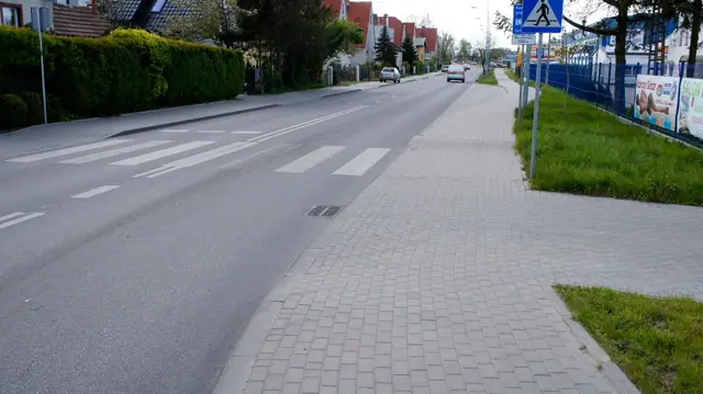 Wybrukowany chodnik prowadzący do oznakowanego przejścia dla pieszych na ukończonej ulicy