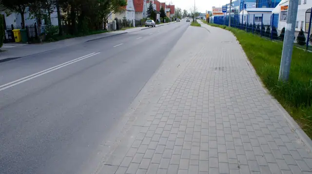 Długi odcinek wykończonego chodnika z pasem zieleni wzdłuż gotowej obwodnicy Kołobrzegu