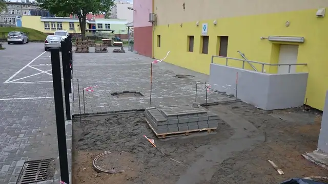 Przygotowana podbudowa z kostki i palety materiałów obok studzienki na Okopowej