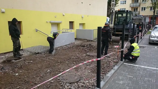 Ekipa pracuje przy studzience kanalizacyjnej, teren zabezpieczony taśmą ostrzegawczą